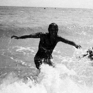 Two children playing in the ocean waves.