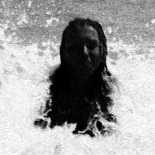 Person emerges from waves in a black and white photo.
