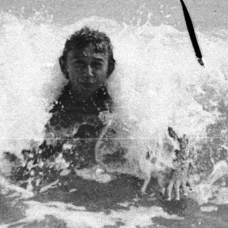 Person submerged in ocean water with waves crashing.