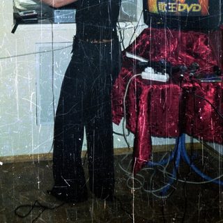 Woman stands near DVD player and red backdrop.