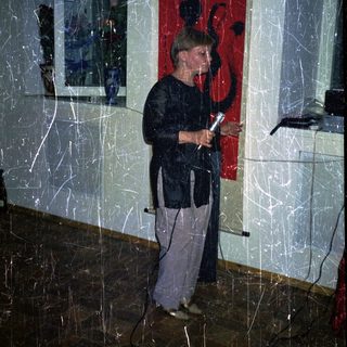 Person speaking into microphone in room with artwork.