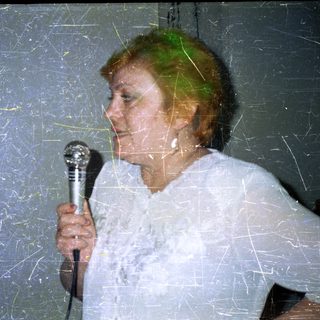 Person holding a microphone against a textured wall.