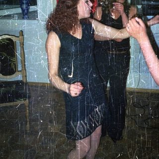 Two women in dresses dancing in a room.