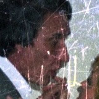 Man embraces a woman in a dimly lit room.