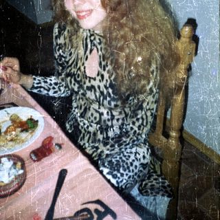 Woman seated at a table with food and drink.