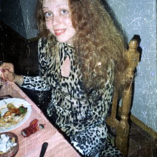 Woman seated at a table with food and drink.