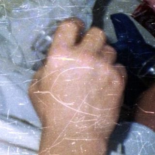 Man lies on floor near window, holding drinks.