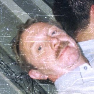 Man lies on floor near window, holding drinks.