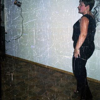 Here's a brief summary of the image: Person stands near a wall with visible damage/scratches.