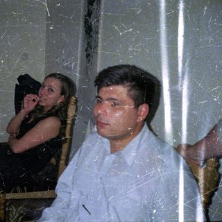 Couple seated at a table with food and drinks.