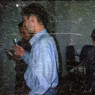 Two figures in a dark room, illuminated by a flashlight.
