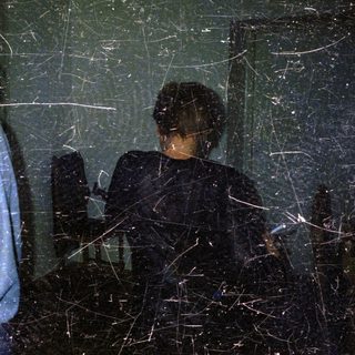 Two figures in a dark room, illuminated by a flashlight.