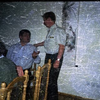 Man sits on stairs as another man stands nearby.
