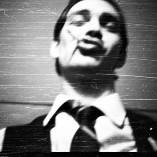 Man in suit speaking at a microphone, looking upward.