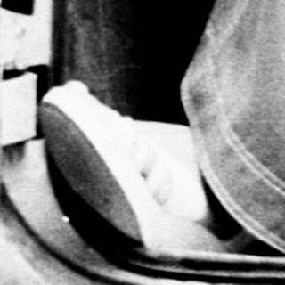 Woman seated in a vintage car, holding the steering wheel.
