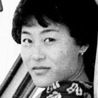 Woman seated in a vintage car, holding the steering wheel.