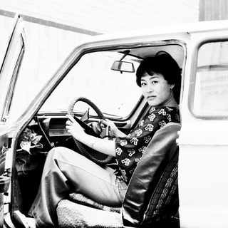 Woman in traditional dress sits in a vintage car.