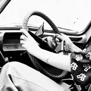 Woman in traditional dress sits in a vintage car.