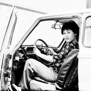 Woman in traditional dress sits in a vintage car.