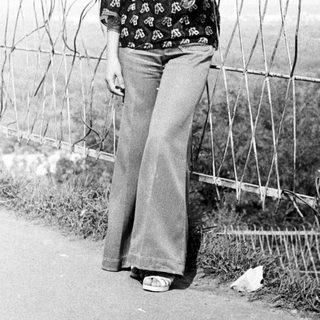 Woman stands near barbed wire fence in a black and white photo.