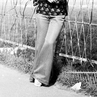 Woman stands near barbed wire fence in a road.