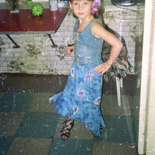 Girl in a blue dress stands in a room.