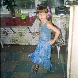 Girl in a blue dress stands in a room.