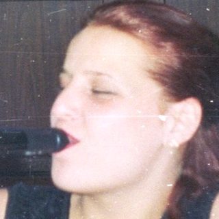 Woman struggles to open a wine bottle, smoking a cigarette.