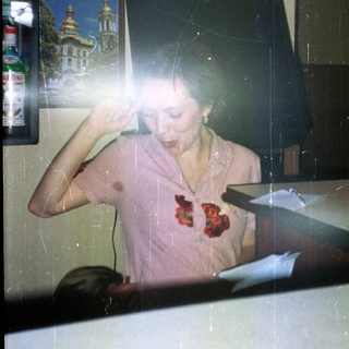 A person sits near a bar, with a Ukrainian image behind.
