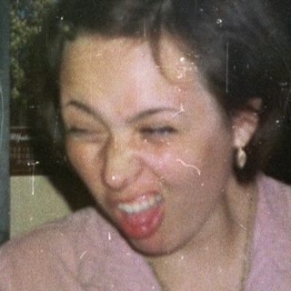 Woman smiles, holding paper in front of a bar.