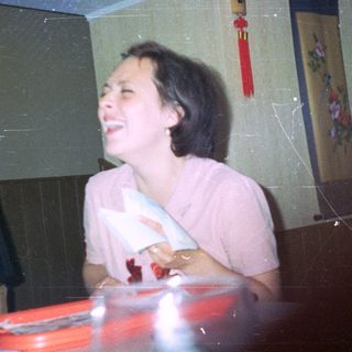 A smiling woman sits at a table in a restaurant.