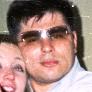 Couple dancing indoors, man wearing sunglasses, woman smiling.