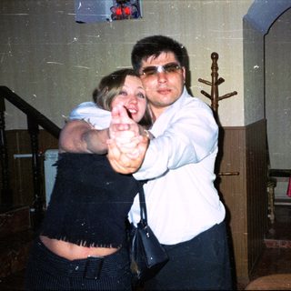 Couple dancing indoors, man wearing sunglasses, woman smiling.