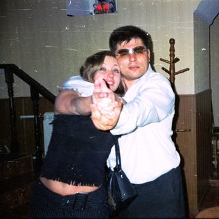 Couple dancing indoors, man wearing sunglasses, woman smiling.