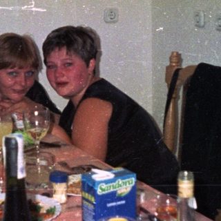 Two women at a table with food and drinks.