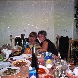 Two women at a table with food and drinks.