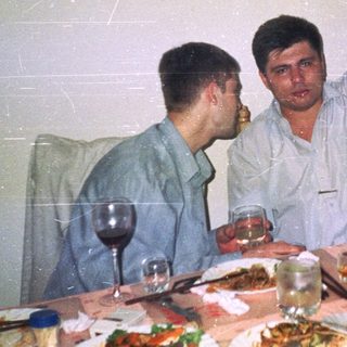 Two men at a table with food and drinks.