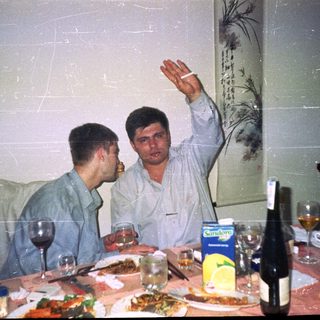 Two men at a table with food and drinks.