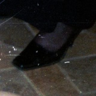 Woman sitting, another lying down, both smiling on tiled floor.
