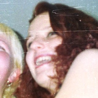 Two women holding a microphone, laughing and looking up.