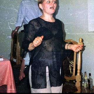 Woman holds a bottle, standing in a decorated room.