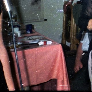 Woman holds a bottle, standing in a decorated room.