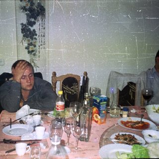 Men seated at a table with food and drinks.