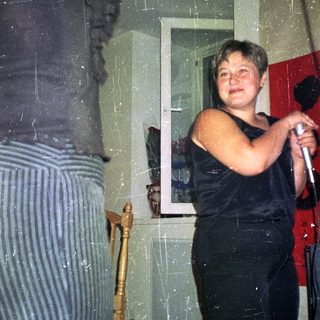 Person holding microphone, standing near a doorway.