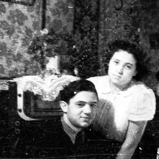Couple posed for portrait, reflected in a vintage mirror.