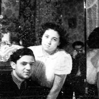 Couple posed for portrait, reflected in a vintage mirror.