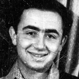 Here's a brief summary of the image: Black and white portrait of a smiling man in a suit.