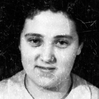 Here's a brief summary of the image: Black and white portrait of a woman with a patterned curtain background.