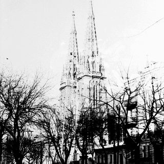 Gothic cathedral with tall spires, partially obscured by trees.