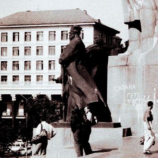 Children play near a statue in a public space.